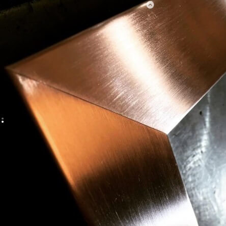 Close up of a folded and welded corner in brushed copper sheet