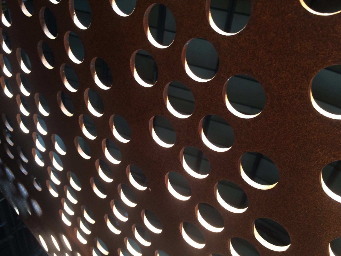 Perforated weathering steel panel backlit by daylight